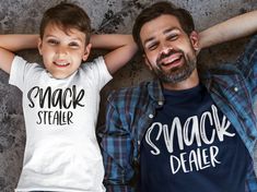 "Celebrate Father's Day with matching shirts for Dad and his little one! These Father-Son Matching Snack Dealer Shirts are the perfect gift for any dad who loves to snack with his mini-me. These shirts feature a playful design with the words \"Snack Dealer\"  OR \"Snack Stealer\" on Dad and Kids shirt(s). It's a fun and unique way to show off the special bond between a father and his child. Not only do these matching shirts make a great Father's Day gift, but they are also perfect for family photos, outings, or any occasion where you want to show off your special relationship with your child. --> OUR SHIRTS <-- - All listings are for 1 single item only unless otherwise specified. Background items are there for show only and are not included( ex. pants,hats,sunglasses etc.) - Our Shirts are Father Son Shirts, Girls Pillows, Kids Pillow Cases, St Patrick Day Shirts, Fathers Day Shirts, Daddy Gifts, Father And Son, Kids Shirts, Sweater Hoodie