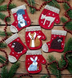 christmas stocking ornaments are hanging on a wooden background with red and white decorations around them