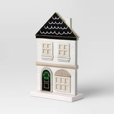 a small white house with a green door and window on the top of it's roof