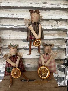 three dolls are holding orange slices on a table