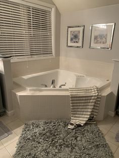 a bathroom with a bathtub, rug and pictures on the wall