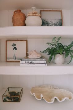 three shelves with vases, books and other items on top of them in a white room