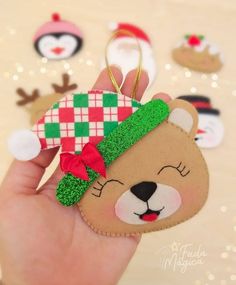 a hand holding a small christmas ornament in the shape of a teddy bear