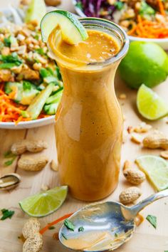 a salad with dressing in a glass jar next to a bowl of vegetables and nuts