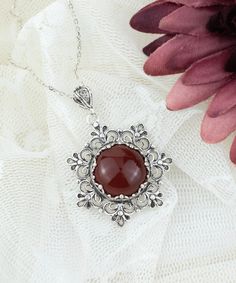 "This beautifully handcrafted filigree art daisy flower pendant feature with Carnelian gemstone. Exquisitely crafted, handmade daisy flower pendant necklace would be your perfect option for anniversary, birthday, thanksgiving or Christmas gift for yourself or loved one.  For gold plated option, visit that link; https://www.etsy.com/FiligranUSA/listing/1401924202 The optional silver chain length is 18.00\" (45.7 cm)  + 2.00\" (5.10 cm) extension.  The Carnelian gemstone diameter is 16 mm, cabochon round-cut.  This metal embroidery filigree pendant is oxidized and highly polished. Comes with a velvet pouch, silver polish cloth and a luxurious gift box. What is Filigree Art? Filigree is made of delicate metal strands that have been skillfully fashioned to create an outstanding combination of Flower Women, Birthday Thanksgiving, Beaded Jewels, Magical Jewelry, Pretty Pendant, Filigree Pendant, Art Pendant, Flower Pendant Necklace, Charm Pendant Necklace