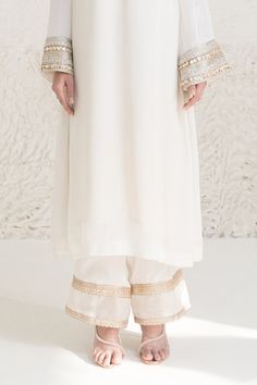 Ivory kurta with sequin, lace embroidered sleeve hem. Paired with gold lace embellished flared pant. - Aza Fashions Elegant White Traditional Wear With Gota Work, Elegant Palazzo Set For Diwali Ceremonies, Elegant Palazzo Set For Diwali And Traditional Ceremonies, Elegant Palazzo Set For Eid And Traditional Ceremonies, White Raw Silk Palazzo Set For Designer Wear, Designer White Raw Silk Palazzo Set, Elegant White Sharara For Traditional Ceremonies, Elegant White Kurta With Gota Work, Elegant Salwar Kameez With Embroidered Border For Reception