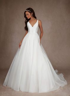 a woman in a white wedding dress standing on a gray background with her back to the camera