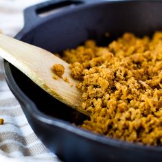 a wooden spoon in a black pan filled with food