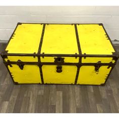 an old yellow trunk is sitting on the floor