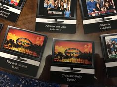 several televisions sitting on top of a wooden table with pictures in front of them