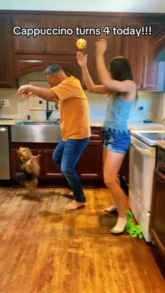 a man and woman dancing in a kitchen with a dog on the floor next to them