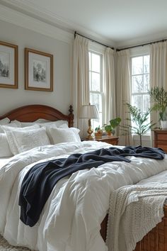 a bed with white comforter and pillows in a bedroom next to two large windows