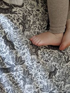 a person laying on top of a bed covered in a black and white bedspread