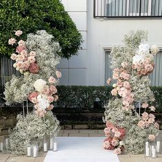 two tall vases filled with flowers on top of a white table cloth covered ground