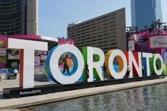 there is a large sign that says toronto in front of the city's buildings