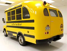 a yellow school bus is parked in a room with white walls and ceiling tiles on the floor