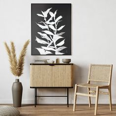 a black and white photo hanging on the wall next to a wooden cabinet with a plant in it