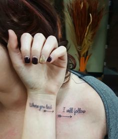 a woman holding her hand up to her face while she has a tattoo on her arm