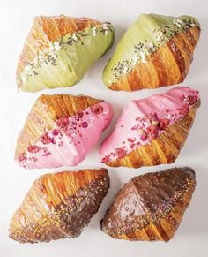 four croissants with different colored frosting and sprinkles on them