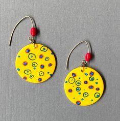 "Happy Bright  yellow with colored dots & circles, accented with a red glass bead, brass V wires. 1& 1/4\" diameter." Handmade Vibrant Yellow Jewelry, Artistic Adjustable Yellow Earrings, Vibrant Handmade Yellow Jewelry, Adjustable Artistic Yellow Earrings, Retro Yellow Dangle Earrings, Playful Adjustable Gold Earrings, Vibrant Yellow Handmade Jewelry, Bohemian Yellow Round Earrings, Yellow Bohemian Round Earrings