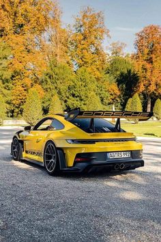 a yellow sports car parked on the side of a road with trees in the background