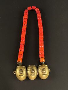 Three-headed brass pendant on orange tile bead necklace. Konyak tribe, Nagaland.