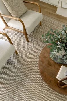 a living room with two chairs and a coffee table on top of a rug in front of a window