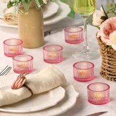 a table set with pink glasses and plates