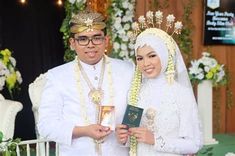 a man and woman standing next to each other in front of a flower covered stage