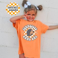 Get the kids game-day ready with our Tennessee Game Day Shirt! Designed on a Comfort Colors tee, this shirt screams TN football vibes, because on Saturdays, it's all about rocking that orange! 🍊 📌Fit: Classic Fit 📌Our designs come to life through a professional direct-to-garment process, where fabric-grade ink is applied directly to the garment, ensuring a seamless integration with the fibers. The outcome is a collection of detailed and full-color prints that not only have a soft feel but als Cotton Short Sleeve T-shirt With Mascot, Orange Cotton T-shirt For Game Day, Cotton Mascot T-shirt With Short Sleeves, Cotton Mascot T-shirt Short Sleeve, Cotton Mascot T-shirt For Sports Fans, Fan Apparel Cotton T-shirt With Mascot, Orange Short Sleeve T-shirt For Game Day, Cotton T-shirt With Mascot For Fan Gear, School Sports Fan T-shirt With Team Name