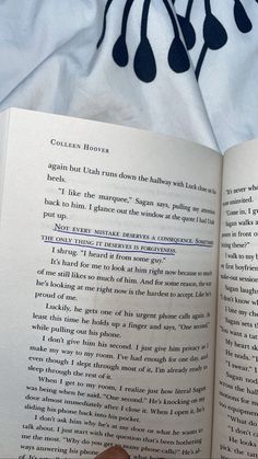 an open book sitting on top of a bed next to a person's hand