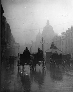 horse drawn carriages on a city street in the rain