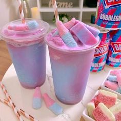 two drinks with marshmallows in them and candy bars next to it on a table