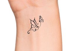 a woman's wrist with a small tattoo design on the left side of her arm