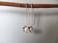 "These long earrings are made with a little white pearl sitting in the center of a flower at the end of a long handmade wire. Flower measures 10mm across 1 3/4\" long Simple and pretty." Sterling Silver Flower Earrings With Pearl Drop, Delicate Flower Shaped Pearl Earrings With Ear Wire, Delicate Flower-shaped Pearl Earrings With Ear Wire, Sterling Silver Flower Pearl Drop Earrings, Long Flowers, Handmade Wire, White Pearl, Long Earrings, A Flower