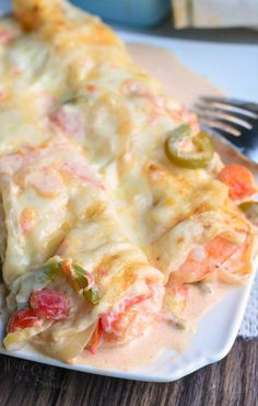 a white plate topped with lasagna covered in cheese and veggies next to a fork