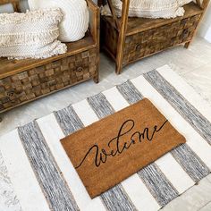 a welcome mat on the floor in front of two wooden benches with pillows and blankets