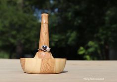 a wooden pipe holder with a bird perched on it's side and trees in the background