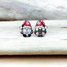 two christmas themed earrings sitting on top of a piece of wood