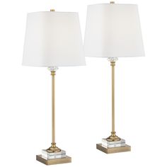 two lamps with white shades on each lamp and one light is gold, the other is clear