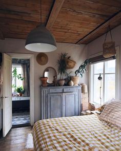 a bed room with a neatly made bed next to a window and a potted plant