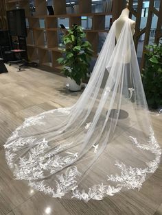 a white wedding veil with flowers on the floor in front of a mannequin