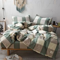 an unmade bed with green and white checkered comforter on the bottom half