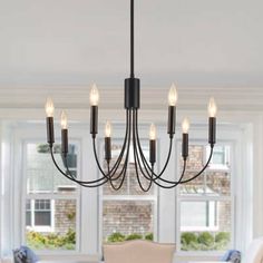 a chandelier hanging over a dining room table with chairs and windows in the background