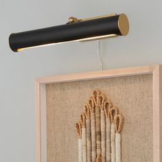 a black and gold wall light hanging from the side of a wooden frame with white curtains on it