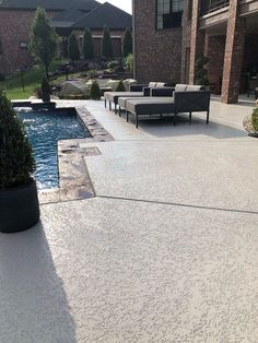 an outdoor living area with couches, tables and a pool in the middle of it