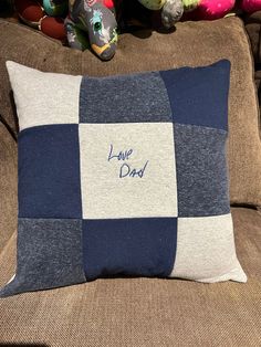 a blue and white pillow sitting on top of a brown couch next to stuffed animals