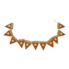 an orange necklace with white beads and wooden triangles on the front, hanging from a hook