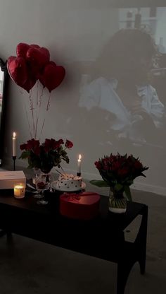 a table with flowers and candles on it in front of a large screen that says love