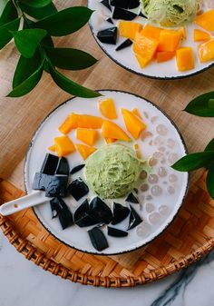 two plates filled with different types of food on top of a wooden table next to green leaves